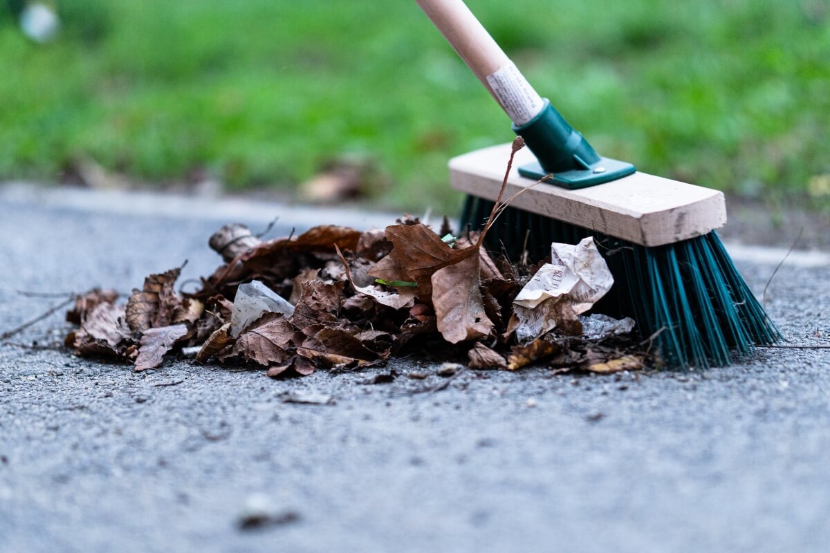 Miotła zmiata liście i śmieci podczas sprzątania terenów przemysłowych.